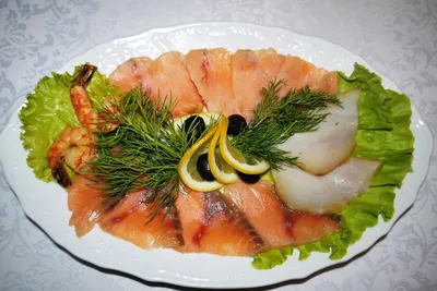 Нарезка красной рыбы на тарелке с оливками, лимоном и розмарином | Премиум  Фото